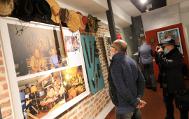 Dwóch mężczyzn ogląda eksponaty na wystawie poświęconej Tony'emu Halikowi, jeden z nich robi zdjęcie