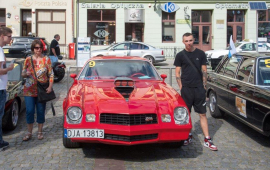 Na zdjęciu: czerwony samochód i osoby oglądające