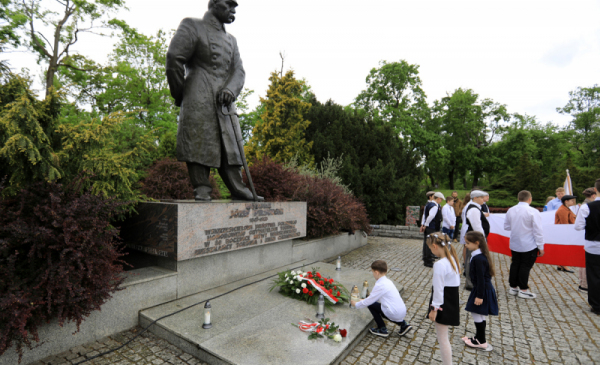 Na zdjęciu: uczniowie ubrani na galowo składają kwiaty pod pomnikiem marszałka Józefa Piłsudskiego