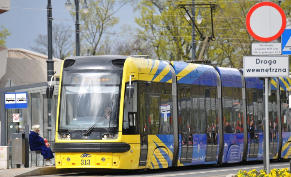Na zdjęciu żółto-niebieski tramwaj stoi na przystanku