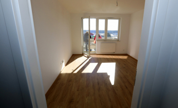 Na zdjęciu: pusty pokój, widać okno i drzwi balkonowe, przez które wpadają promienie słońca