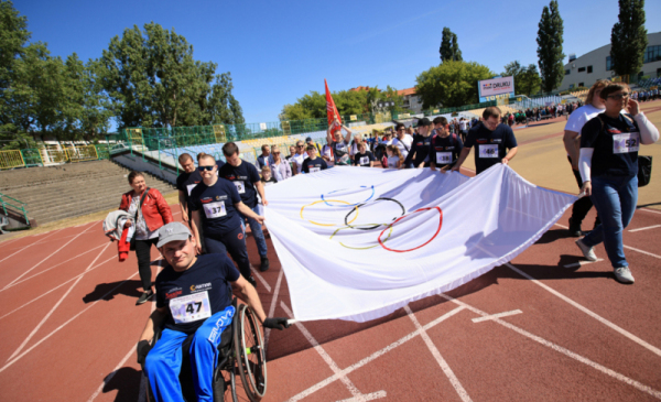 Na zdjęciu: osoby z niepełnosprawnościami niosą flagę olimpijską