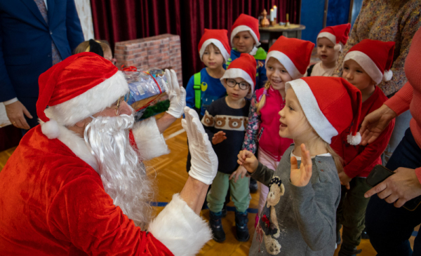 Na zdjęciu: św. Mikołaj przybija piątkę dzieciom ubranym w czapki Mikołaja