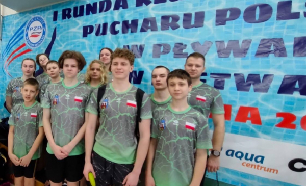 Pływacy toruńskiego klubu Laguna 24 stoją z medalami pod banerem zawodów