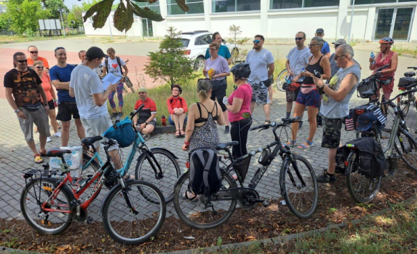 Na zdjęciu: rowerzyści stoją i słuchają przewodnika
