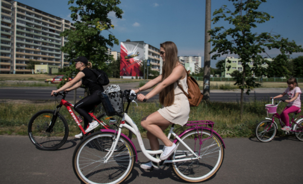 Na zdjęciu: dziewczyna w kasku jedzie na białym rowerze