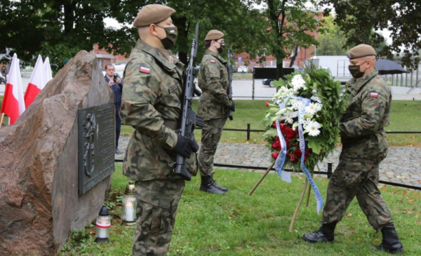 Żołnierze składają wieniec biało-czerwonych kwiatów pod obeliskiem