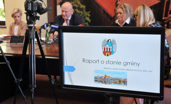 na zdjęciu: podczas konferencji prasowej na pierwszym planie monitor ze stroną tytułową prezentacji z Raportem o stanie gminy
