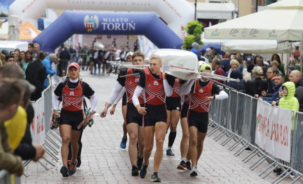 Na zdjęciu zawodnicy Run & Row 2019 biegną z łodzią na barkach przez ulice toruńskiej starówki