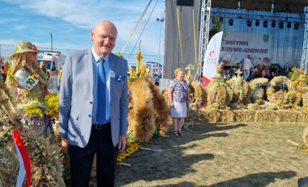 Na zdjęciu: uśmiechnięty prezydent Michał Zaleski stoi przy wieńcach dożynkowychh