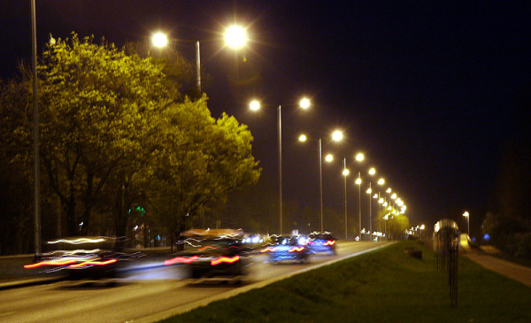 Samochody jadące wzdłuż oświetlonej nocą Szosy Lubickiej