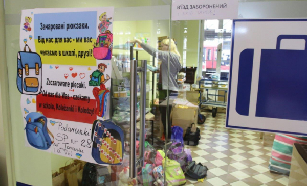 Na zdjęciu: przez szkolane drzwo widac pokój dla dzieci z zabawkami i kolorymi plecakami