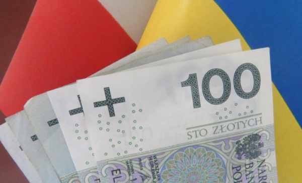 Na zdjęciu banknoty stuzłotowe w tle flaga Polski i Ukrainy