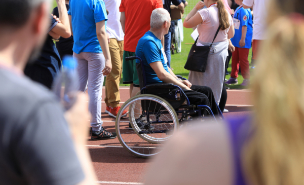 Meżczyzna na wózku inwalidzkim wśród grupy ludzi podczas imprezy sportowej