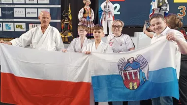 Zawodnicy AKKT Toruń z flagami Polski i Torunia