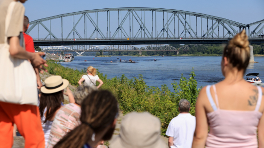 Na zdjęciu ludzie na Błoniach Nadwiślańskich patrzą w kierunku toruńskich mostów