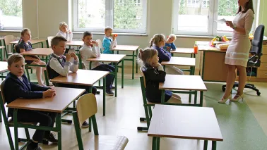 Klasa szkolna i uczniowie siedzący w ławkach.