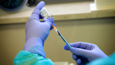 Na zdjęciu osoba w rękawiczkach pobiera szczepionkę do strzykawki