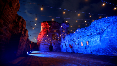 Na zdjęciu podświetlone na kolor czerwony i niebieski mury zamku krzyżackiego