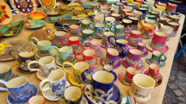 Na zdj: stół z ceramicznymi, kolorowymi naczyniami