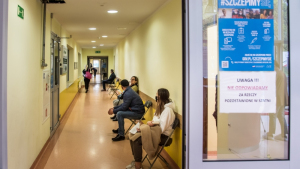 Na zdjęciu osoby czekają na korytarzu na szczepienie
