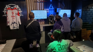 Na zdjęciu: młodzi chłopcy siedzą przed monitorem i grają w e-hokeja