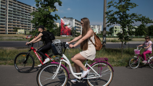 Na zdjęciu: dziewczyna w kasku jedzie na białym rowerze