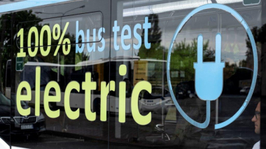 Na zdjęciu szyba autobusu elektrycznego z napisem "100 percent electric bus test"