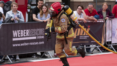 Na zdjęciu: strażak biegnie z wężem strażackim