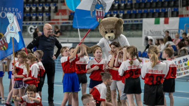 Na zdjęciu: dzieci w hali sportowej stoją z flagą miasta