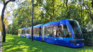 Zdjęcie przedstawia tramwaj przejeżdżający nowym zielonym torowiskiem
