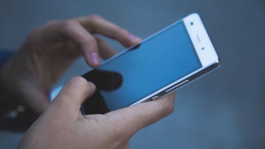 Ręce trzymające telefon komórkowy na niebieskim tle