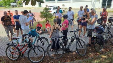 Na zdjęciu: rowerzyści stoją i słuchają przewodnika