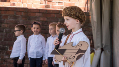 Na zdjęciu: chłopiec przebrany za flisaka trzyma zrobione z tekstury skrzypce