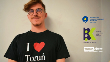 Uśmiechnięty chłopak w czarnej koszulce z napisem I love Toruń i logotypami