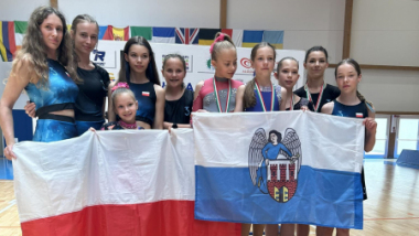 Na zdjęciu: grupa dziewcząt stoi na podium, trzymają biało-czerwoną flagę Polski i biało-niebieską z herbem Torunia