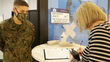 Na zdjęciu żołnierz WOT patrzy jak kobieta wypełnia formularz