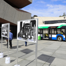 Na zdjęciu wystawa pokazująca przekrój toruńskiego taboru autobusowego, w tle autobus elektryczny