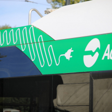 Na zdjęciu zielona naklejka z białym przewodem elektrycznym na autobusie