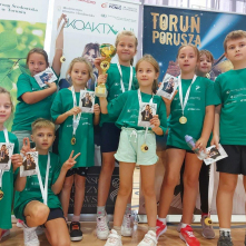 Na zdjęciu: dzieci w zielonych koszulkach pokazują medale i puchary