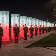 Na zdjęciu żołnierze z pochodniami stoją przy biało-czerwonych tablicach
