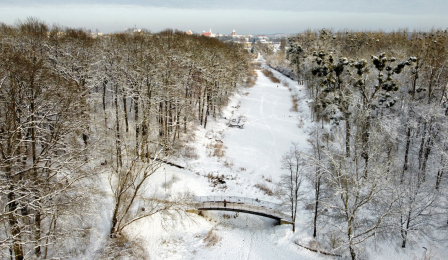 Widok z drona na ośnieżony Park Miejski i mostek na Martówce