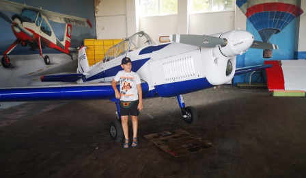 Na zdjęciu chłopiec stoi przy szybowcu na Lotnisku Aeroklubu Pomorskiego