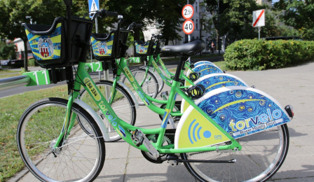 Kilka zielono-niebieskich rowerów na stacji wypożyczeń
