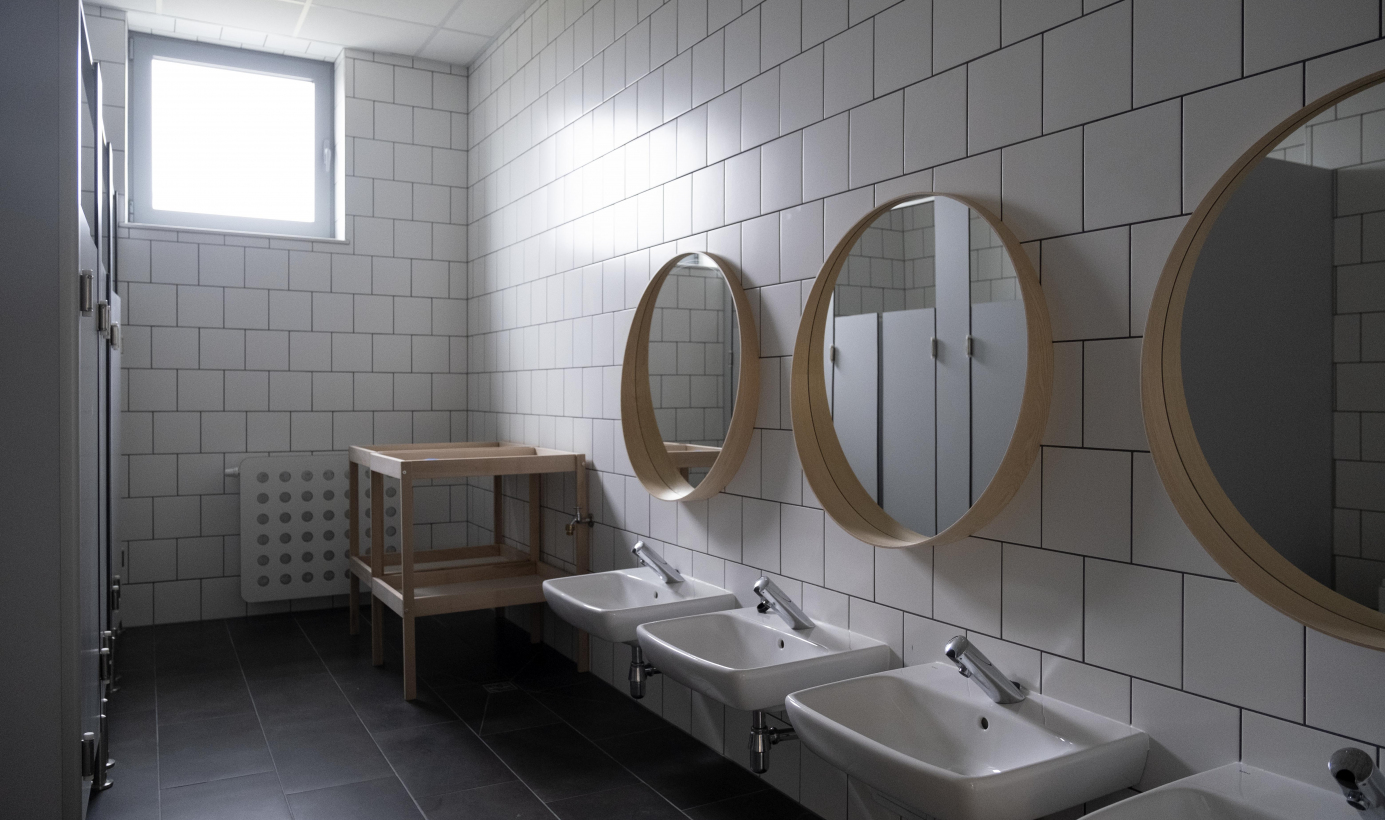 Na zdjęciu widać łazienkę w nowym żłobku, nisko usytuowane umywalki, a nad nimi okrągłe lustra w drewnianych ramach